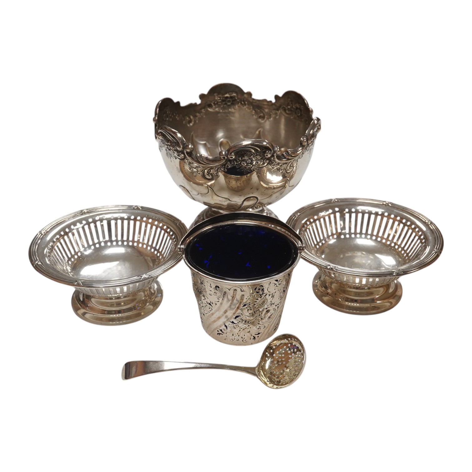 A George III small silver sugar basket, London, 1810, with blue glass liner, 57mm, a George III silver sifter spoon, a pair of silver bonbon dishes and an Edwardian small rose bowl, 16.9oz. Condition - poor to fair to go